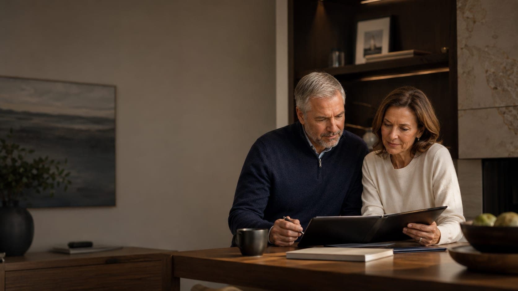 A couple in their sixties reviewing their savings together at the dining table